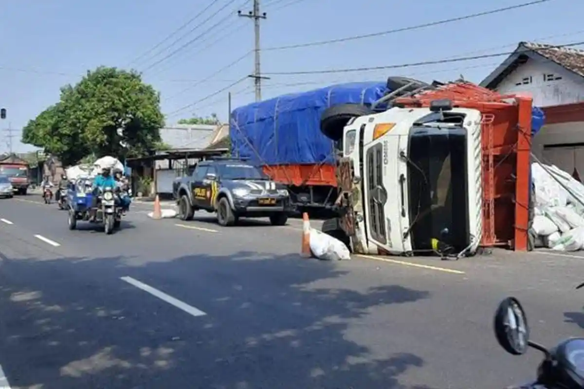 Gegara Anak Sekolah, Truk Gandeng Muatan Pakan Ikan Terguling di Jalan Raya Gampengrejo di Kediri