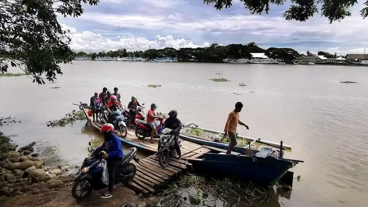 FOTO: Kurir JNE Lintas Sungai Jeneberang Antar Paket Pelanggan