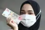 Warga Memperlihatkan Uang Kertas Baru Pecahan Rp 75.000
