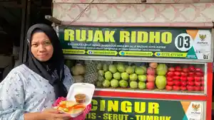 Pedagang-UMKM-Rujak-di-simpang-Seraya-Dewi-memperlihatkan-hasil-olahan-di-depan-gerobak-usahanya.jpg