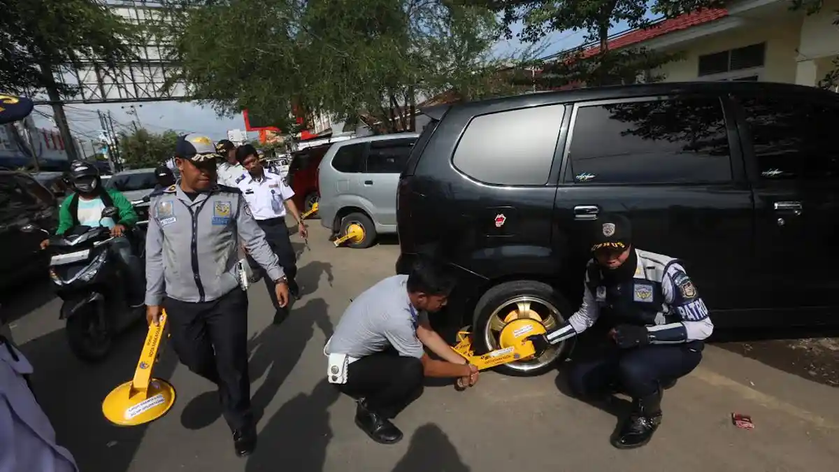 FOTO: Dishup Makassar Gembok Roda Mobil Parkir di Badan Jalan