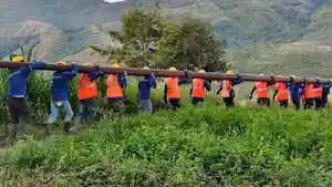 Para-pekerja-bergotong-royong-memikul-tiang-listrik-melintasi-berbagai-medan.jpg