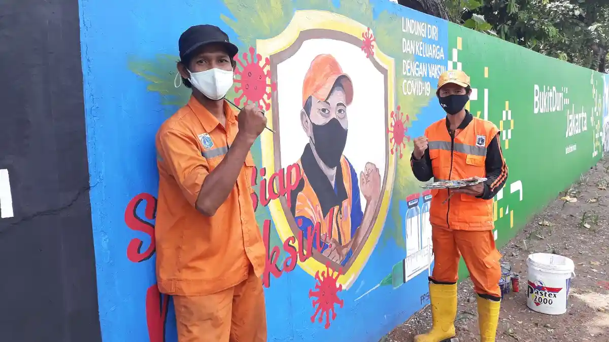 Lukis Wajah Temannya di Tembok, Petugas PPSU Bukit Duri Ajak Warga Bersedia Divaksin Covid-19