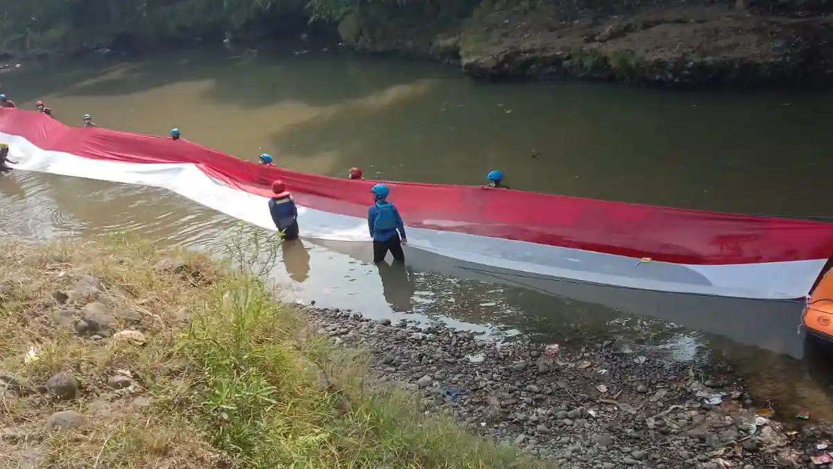 Peringati HUT ke-76 RI, Bendera Merah Putih Sepanjang 33 Meter Dibentangkan di Atas Kali Ciliwung