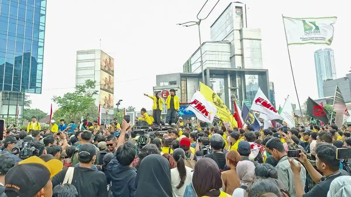 Massa aksi unjuk rasa berkerumun di kawasan Bundaran HI, Jakarta, dengan membawa bendera-bendera organisasi; sejumlah peserta tampak mengenakan jaket kuning