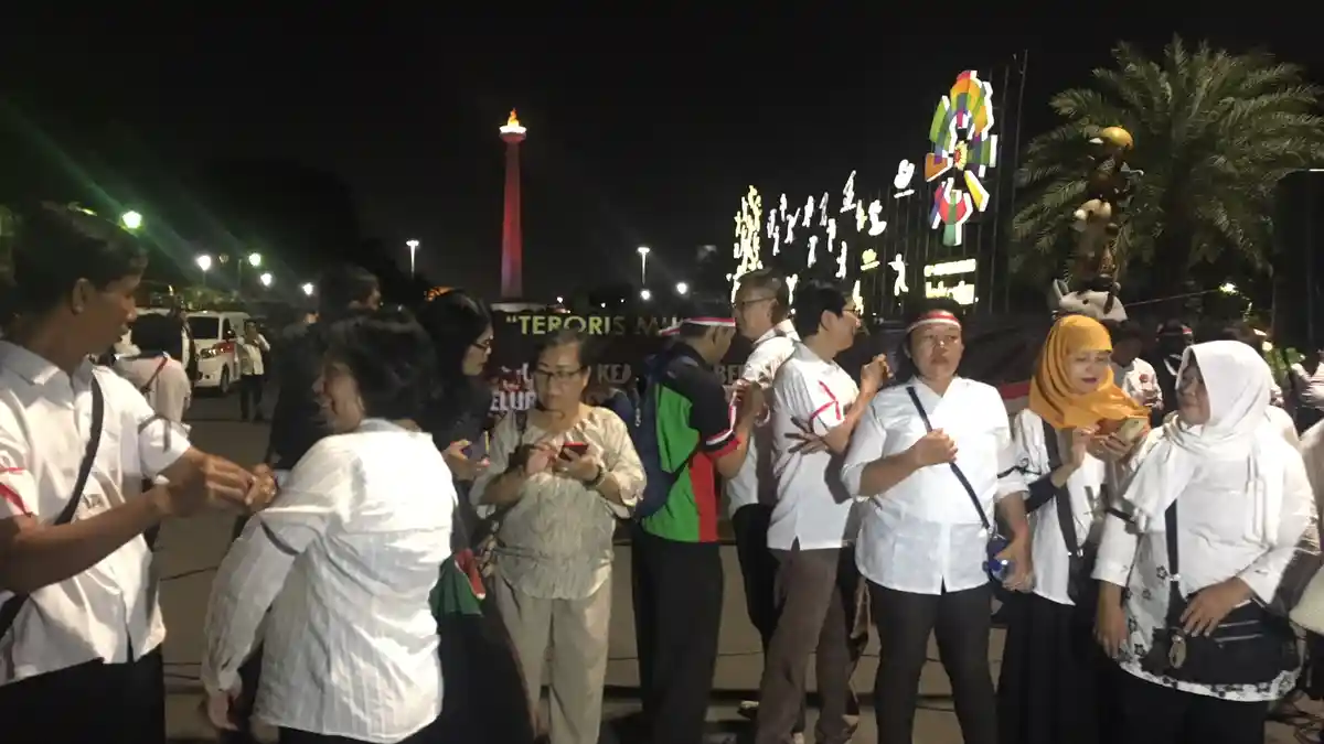 Massa Berkaus Putih Mulai Padati Monas Malam Ini untuk Nyalakan Lilin